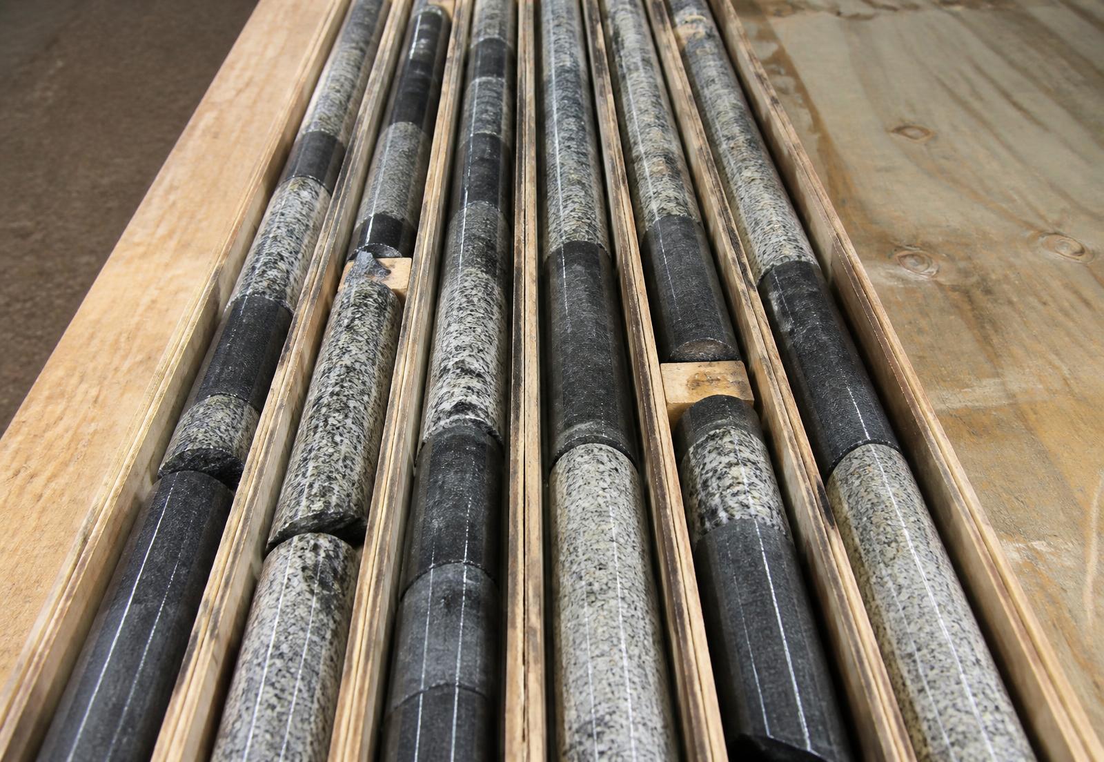 Diamond drill core in a wooden core box showing dark semi-massive ilmenite alternating with pale plagioclase-rich gabbronorite
